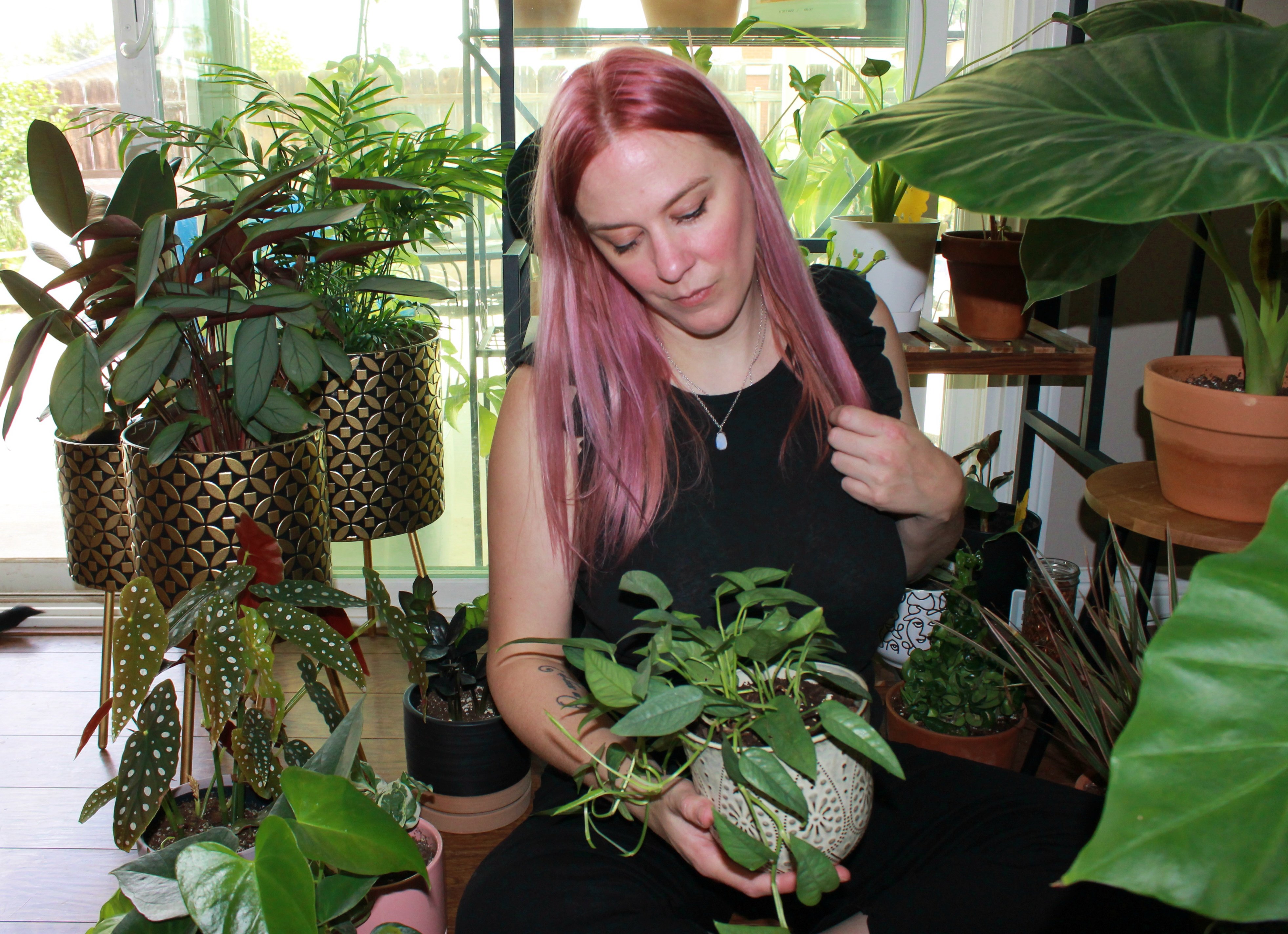woman with pink hair sitting among plants